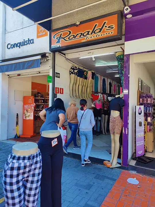 Clientes entrando na Ronald's Fashion, com manequins e araras na entrada