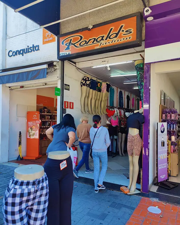 Clientes entrando na Ronald's Fashion, com manequins e araras na entrada