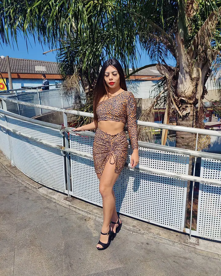 Modelo com cropped e saia de estampa de onça numa passarela ao ar livre
