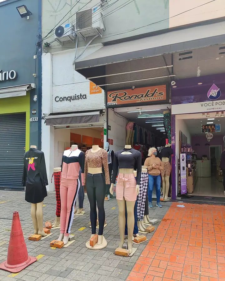 Fachada da Ronald's Fashion com o letreiro laranja e manequins vestidos na calçada